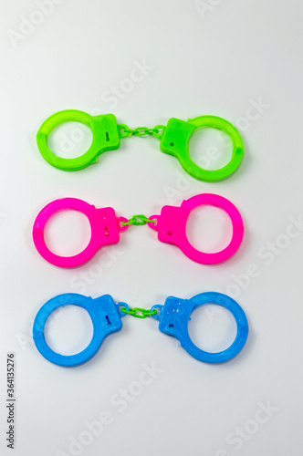 The toy handcuffs are available in green, pink and blue. On a white background.