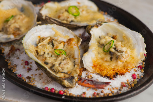 Oysters Rockefeller. Oysters topped with cheese, cream, garlic onions oven baked and garnished with fresh diced jalapeños. Classic American restaurant or French bistro appetizer.