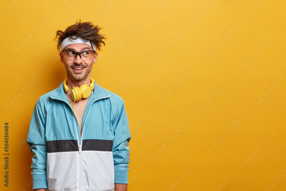 Fotografie Fitness sporty guy in good mood, looks aside with motivation, enjoys workout and