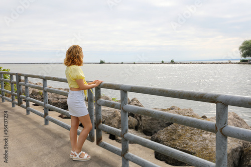Attractive young woman enjoying view of Lake Ontario. She is taking a break from her early morning walk.
