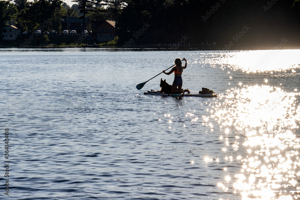 Naklejka premium paddle boarding on lake with dog
