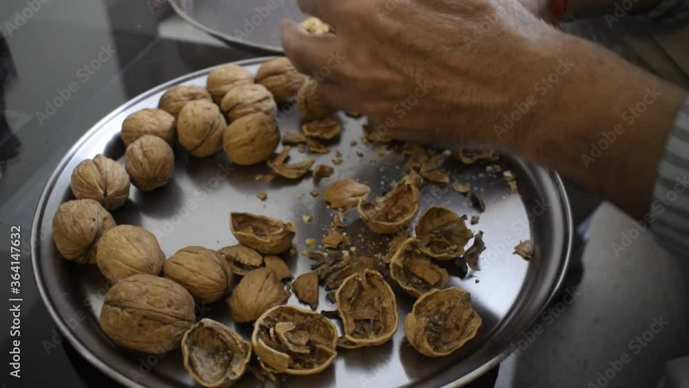 Man breaking the walnut shells manually. Walnut is known for its high