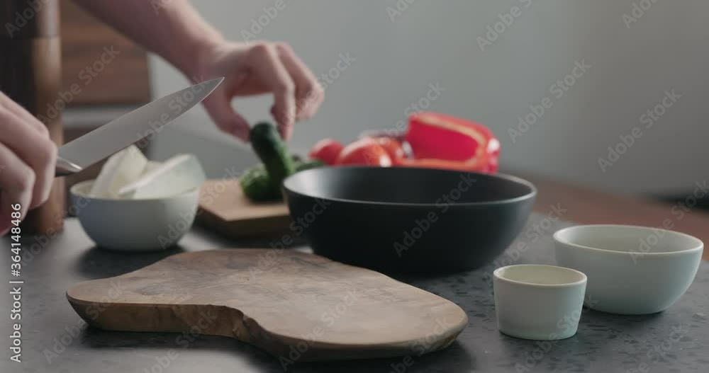 Slow motion slide shot of man put cucumber on olive wood board for greek salad Slow motion slide shot of man put cucumber on olive wood board for greek salad