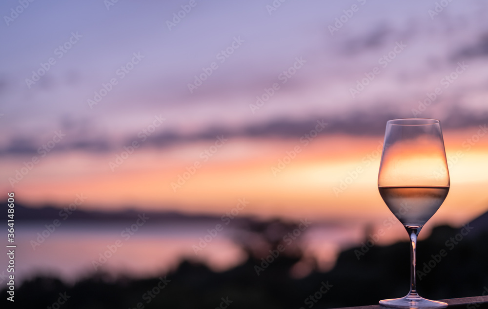 Obraz premium A Glass of white wine with a beautiful sunset in the background