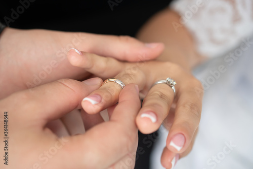 The groom puts the wedding ring on the finger of his bride. Selective focus. Wedding concept  traditions.