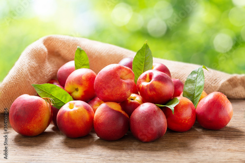 Bild auf Leinwand fresh ripe nectarines with leaves on a wooden table