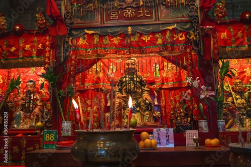 This image shows candles and incense burning in a beautiful red buddha temple. photo