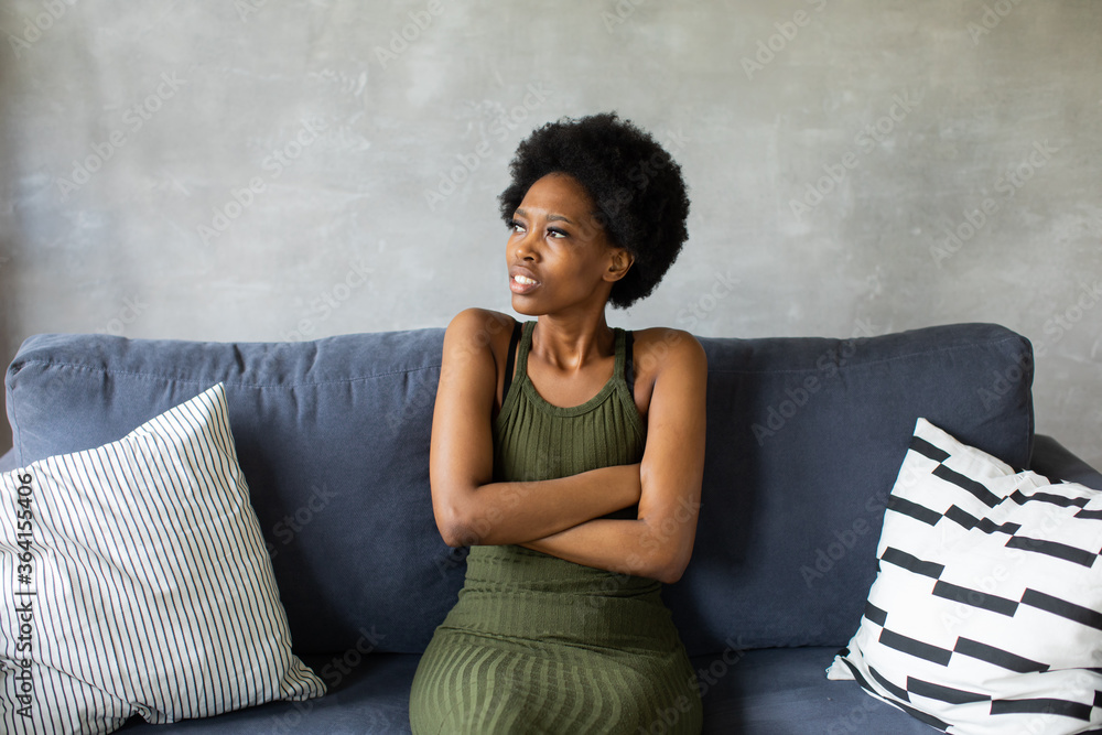 Unhappy African American woman sit on the sofa, the girl is very upset sitting on the couch of her apartment. Unhappy African American woman sit on the sofa, the girl is very upset sitting on the couch of her apartment.