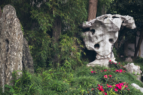 Canvas Print Flowers around a stone statue, city of Shanghai China.