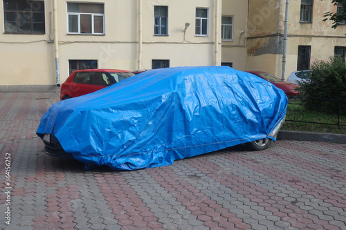 a car under a blue cape parked in the yard