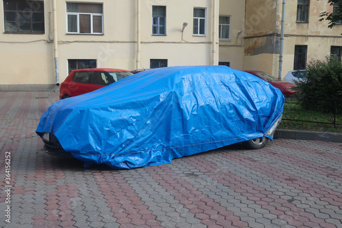 Fotografija a car under a blue cape parked in the yard