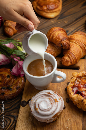 Assorted pastries, croissants, buns. On a brown wooden table. 