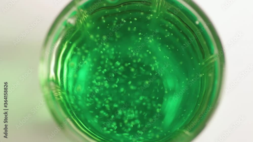 Green soda is poured from the bottle into the glass and the bubbles rise up Green soda is poured from the bottle into the glass and the bubbles rise up
