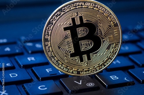 Golden bitcoin coin on laptop keyboard