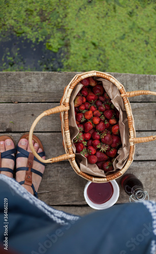 female legs and a wicker basket full of strawberries,view from above