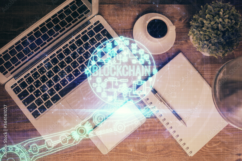 Blockchain theme hologram drawings over computer on the desktop background. Top view. Double exposure. Blockchain theme hologram drawings over computer on the desktop background. Top view. Double exposure.