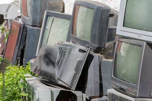 old dirty broken electronics dump overgrown with grass photo