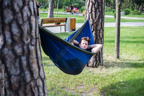 Young guy has a rest in summer in a hammock