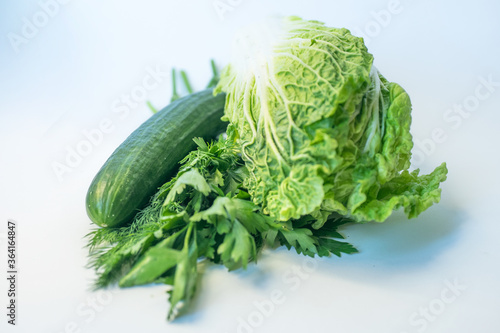 Fresh green vegetables: pak choi (chinese cabbage) and cucumber on a white background. Fresh, green vegetable, close-up shot. Healthy lifestyle theme, kitchen scene. Copy space. Minimalism concept 