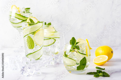 Alcohol drink (gin tonic cocktail) in a variety of glasses with lemon, cucumber, mint leaves and ice. Iced drink with lemon.