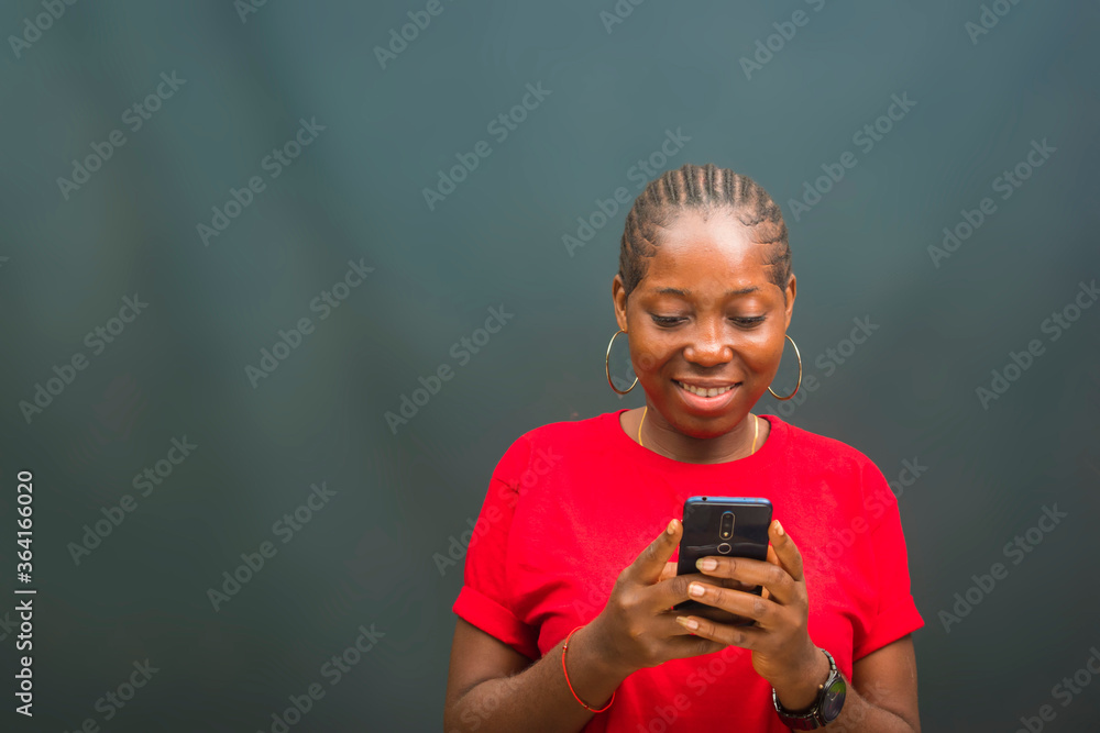 young beautiful african lady feeling excited as she is operating her cellphone