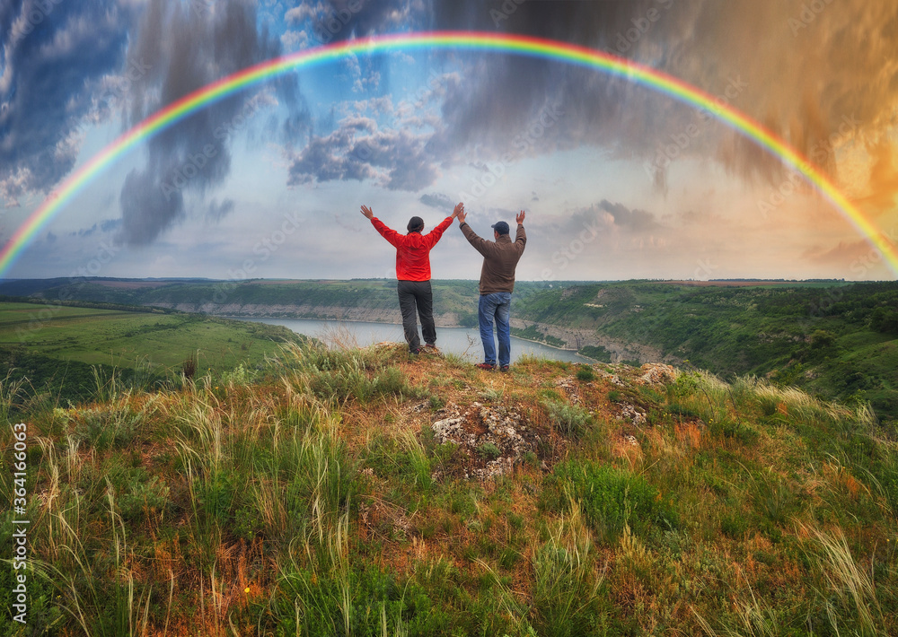 Woman and man Looking At Rainbow. rainbow over river canyon
Woman and man Looking At Rainbow. rainbow over river canyon