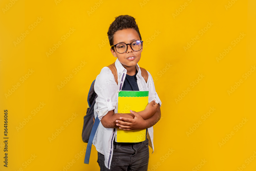 An African-American man stands on a yellow background with a backpack An African-American man stands on a yellow background with a backpack