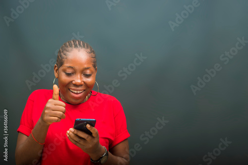 Quadro em tela young beautiful african lady feeling excited as she is operating her cellphone