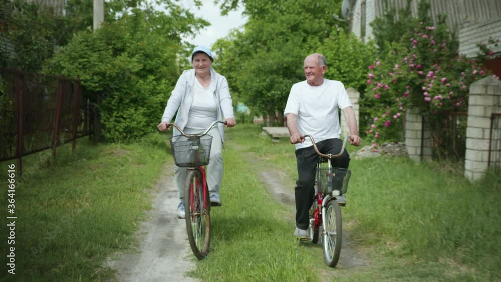 outdoor activities, happy elderly man and woman enjoying cycling, an old joyful couple have fun while cycling on weekend in countryside