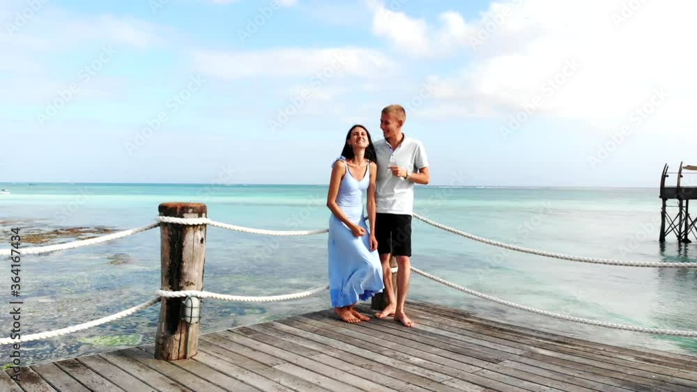 Happy married couple staying on amazing wooden bridge on seascape background, disputting, gesturing with hands and smiling. Couple in love joking and running, beautiful people enjoying their honeymoon Happy married couple staying on amazing wooden bridge on seascape background, disputting, gesturing with hands and smiling. Couple in love joking and running, beautiful people enjoying their honeymoon