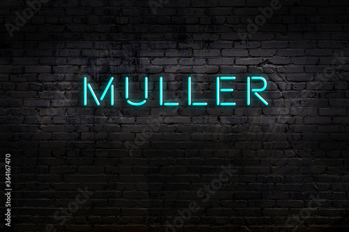 Neon sign. Word muller against brick wall. Night view