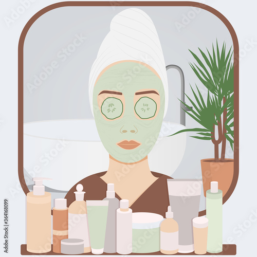 Young woman looks at the mirror in bathroom apply cosmetic face mask or cream on skin. Skin care and treatment spa procedure at home. Girl head in towel at mirror view.