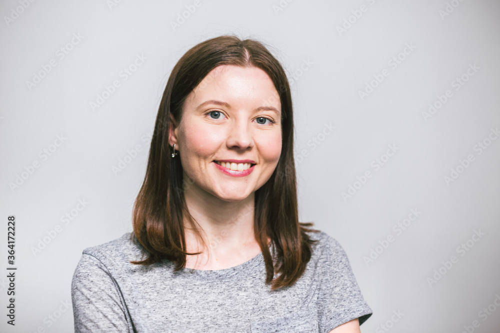 portrait of stylish young pretty Caucasian woman smiling in grey t-shirt on white studio background, isolated, natural look, long brown hair portrait of stylish young pretty Caucasian woman smiling in grey t-shirt on white studio background, isolated, natural look, long brown hair