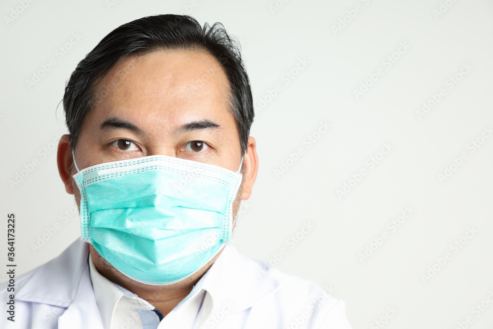 Close-up Asian man looks self-confident wearing a white shirt, wearing a medical mask to prevent the virus, looking at the camera isolated on a white background. With copy space on the right-hand side Close-up Asian man looks self-confident wearing a white shirt, wearing a medical mask to prevent the virus, looking at the camera isolated on a white background. With copy space on the right-hand side