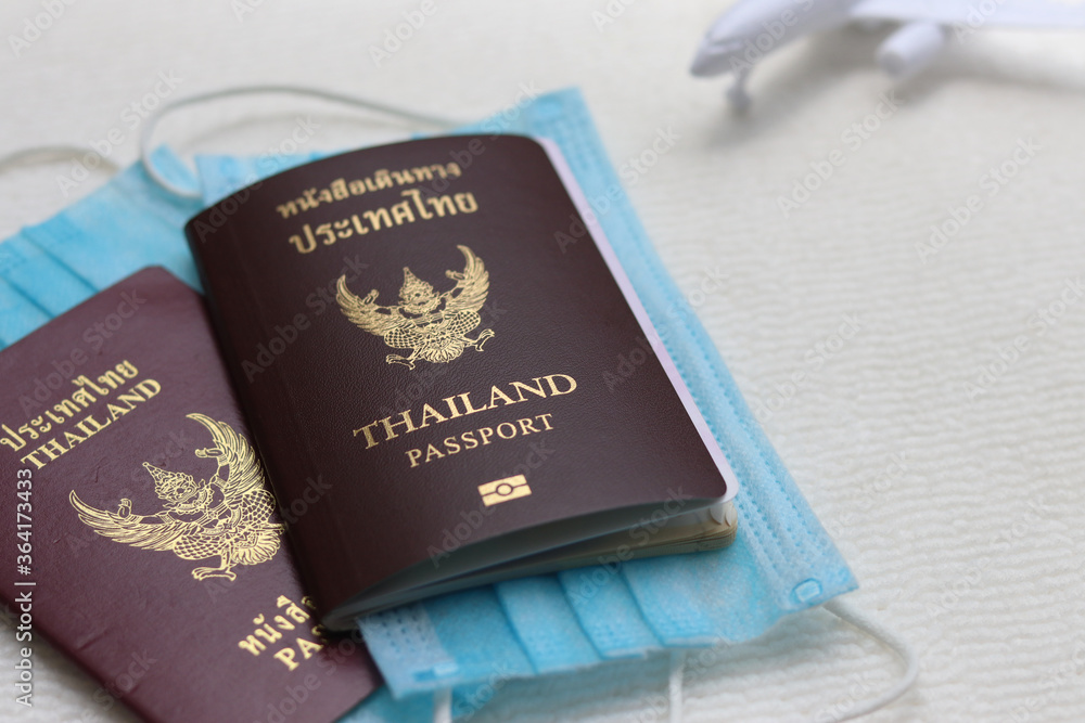 Thai Passports with medical face masks and blurred airplane on white background. Lifestyle and traveling concept in New Normal after Covid-19 / Coronavirus pandemic. Thai Passports with medical face masks and blurred airplane on white background. Lifestyle and traveling concept in New Normal after Covid-19 / Coronavirus pandemic.