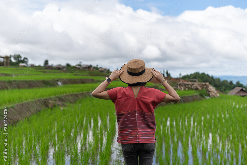 Young female traveler with hat enjoying beautiful view rice fields on terraced of Ban Pa Bong Piang, Chiangmai, Thailand