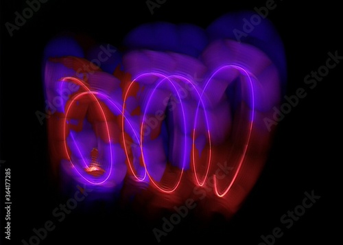 light painting abstract background. curves and waves of purple and red light against a black background