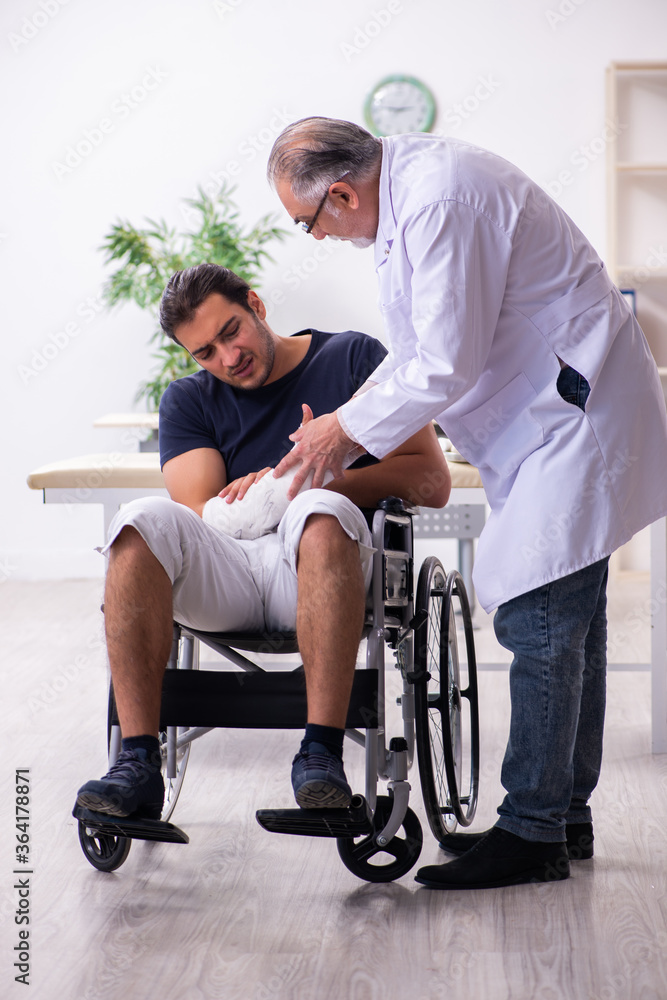 Young injured man visiting experienced male doctor traumatologis Young injured man visiting experienced male doctor traumatologis