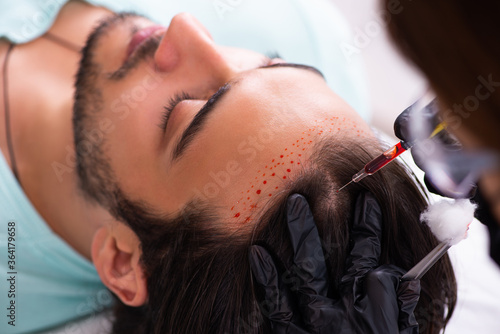 Young man visiting female beautician in hair transplantation con