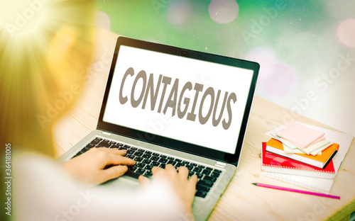 Conceptual hand writing showing Contagious. Concept meaning transmissible by direct or indirect contact with infected an individual Modern gadgets white screen under colorful bokeh background photo