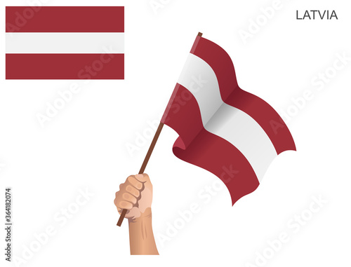 Latvian country flag raised with a stick held by hand to inflame the spirit of statehood