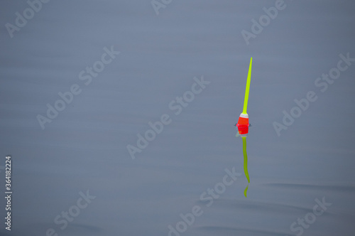Red and yellow fishing bobber isolated in calm water