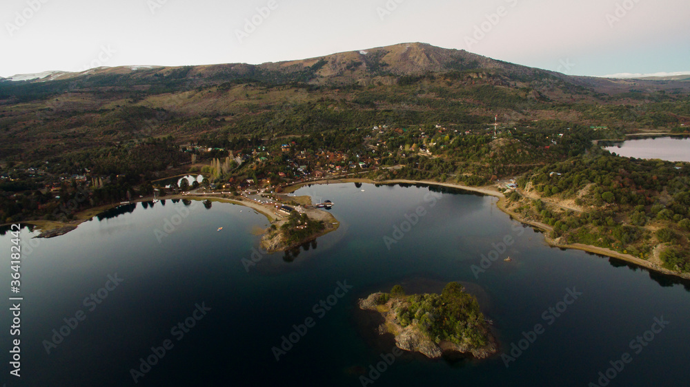 Tourism. The lake at sunset. Aerial view of the tranquil village Pehuenia. The bay, harbor, island, forest and mountains at nightfall. 