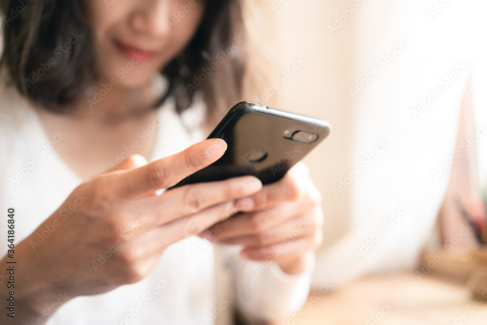 Close up hands of woman using smartphone chatting and searching information with blurry smiley face background. copy space of technology business and social distancing concept Close up hands of woman using smartphone chatting and searching information with blurry smiley face background. copy space of technology business and social distancing concept
