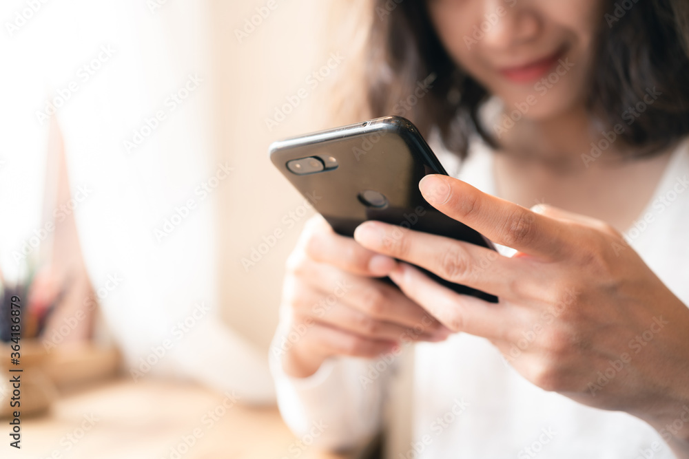 Close up hands of woman using smartphone chatting and searching information with blurry smiley face background. copy space of technology business and social distancing concept Close up hands of woman using smartphone chatting and searching information with blurry smiley face background. copy space of technology business and social distancing concept