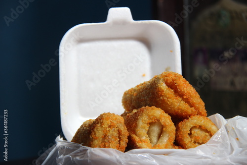 crispy roll cake with egg and sausage flavor. snacks with white and pastic containers on a wooden table photo