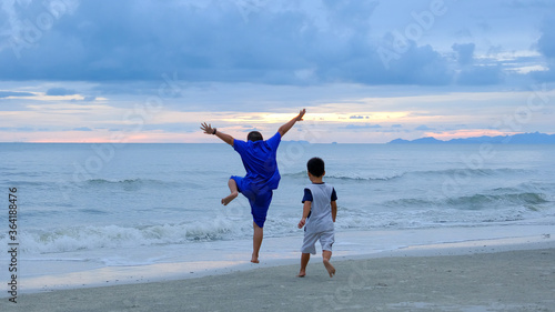 Blue sky and two children enjoy and action jumping on the beach.