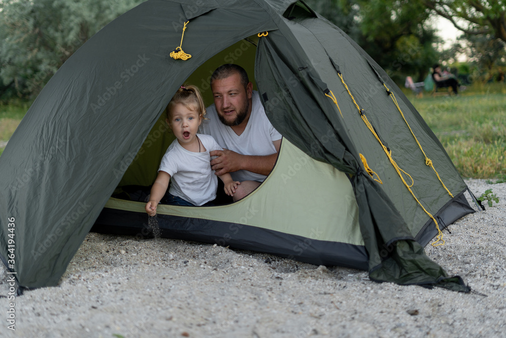 father with daughter in a tent. A little girl is looking at us from a tent. She is full of emotions.