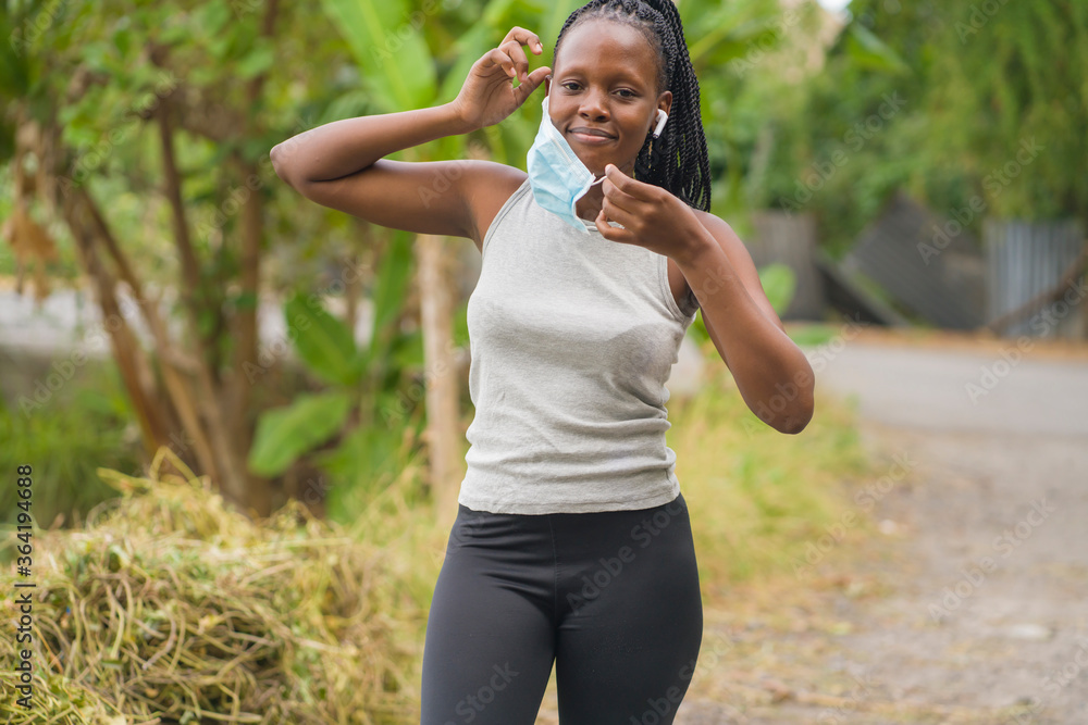 runner girl lifestyle during post quarantine new normal times - young attractive and fit black afro American woman adjusting face mask before running workout