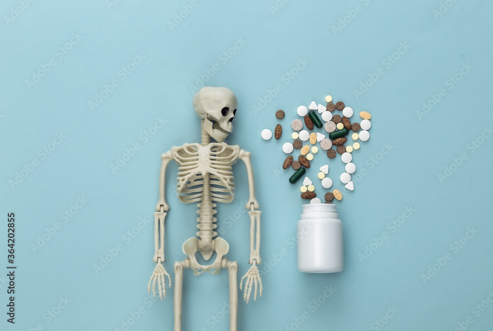 Medicine or narcotic concept concept. Skeleton and pills bottle on blue background. Top view Medicine or narcotic concept concept. Skeleton and pills bottle on blue background. Top view